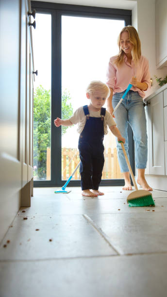istock Mother With Young Son At Home In Kitchen Helping With Housework Sweeping Floor 2151909417