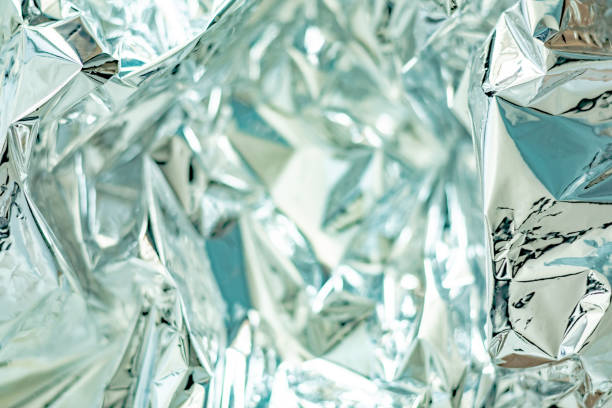 Glare surface. Crumpled aluminum foil. Crinkled background. Colored glitter. Selective soft focus