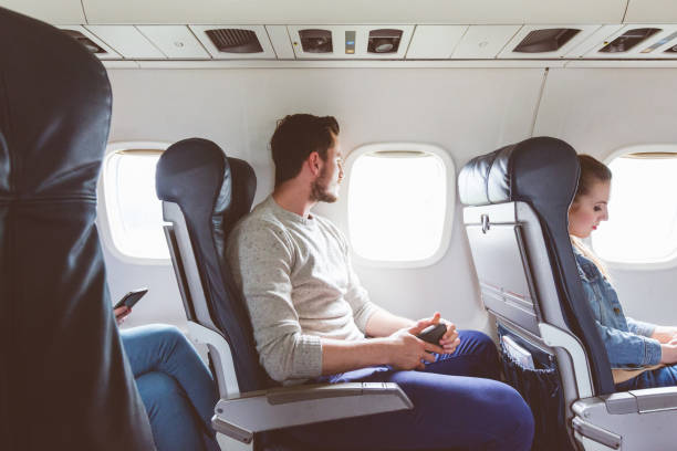 istock Young man sitting in airplane near window 2151914116
