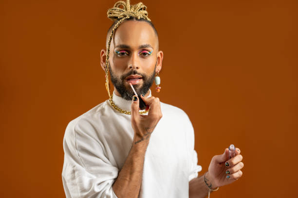 istock African american gay applying make up isolated on brown background 2151917870