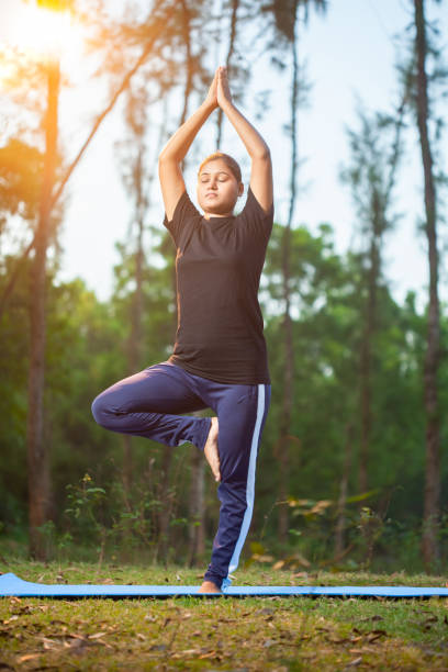 istock indian women practicing Vrksasana or tree pose at outdoor during early morning 2151920170
