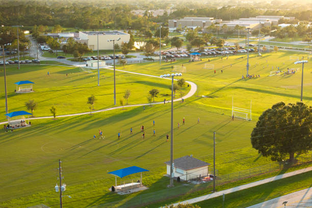 School children playing soccer game during physical exercise on school stadium at sunset. Active way of life concept.