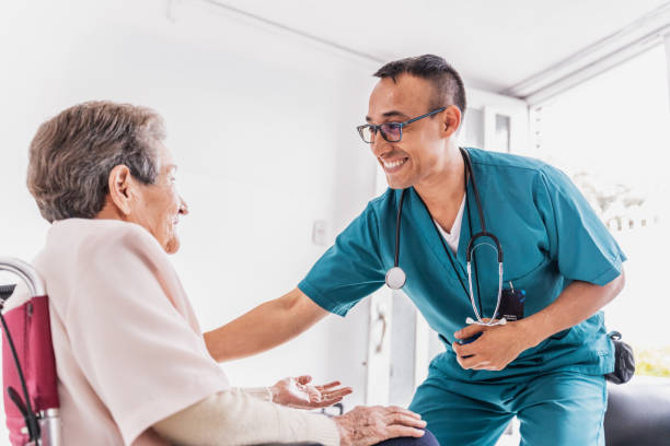 fotografii de stoc, fotografii și imagini scutite de redevențe cu îngrijitoare vorbind cu o femeie în vârstă în scaun cu rotile la ospiciu - asistentă medicală de sex masculin