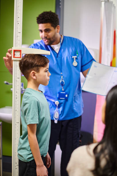 male nurse with mother and child patient looking at height chart male nurse with and child patient looking at height chart boy height measure stock pictures, royalty-free photos & images