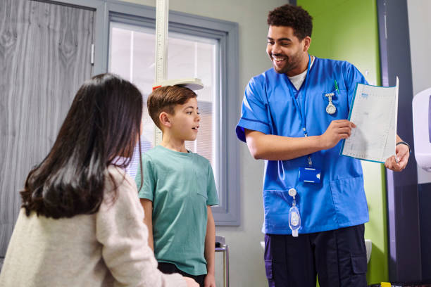 centile height chart paediatrics male nurse with and child patient looking at height chart boy height measure stock pictures, royalty-free photos & images