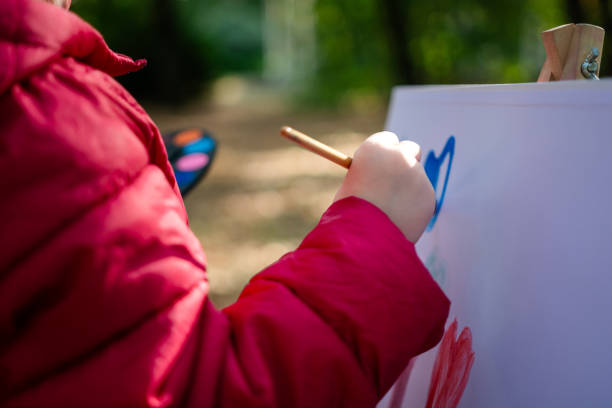 Close-up of child's hands painting whit watercolors in public park