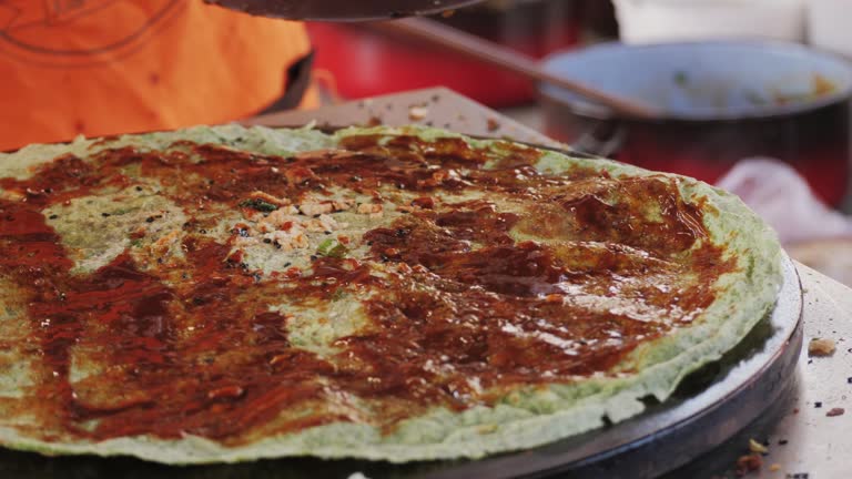 Chinese traditional street food Jianbing close-up. Cooking asian crepe or pancake Jianbing, one of China most popular street breakfasts
