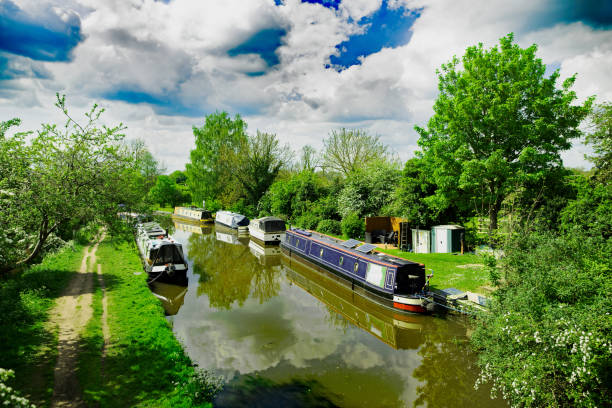 Colorful autumn trees reflect in canal beside peaceful narrowboat and path. High quality photo