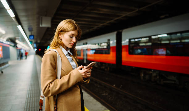istock Young long-haired woman messaging phone while standing on the subway 2151923398