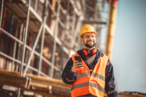istock Construction site manager standing  wearing safety vest and helmet,using his phone at construction site. 2151925205