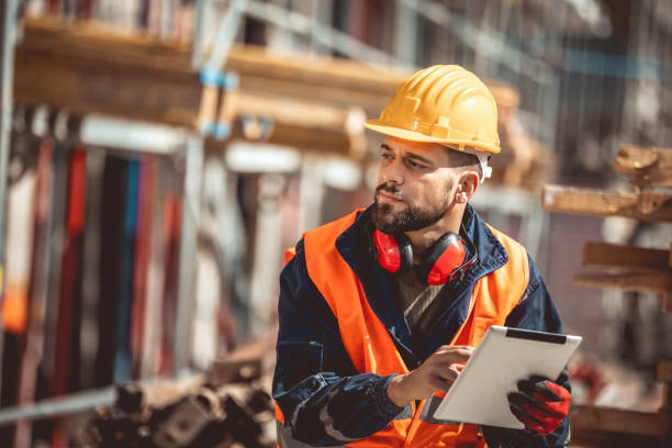 istock Construction site manager standing  wearing safety vest and helmet,using his tablet at construction site. 2151925276