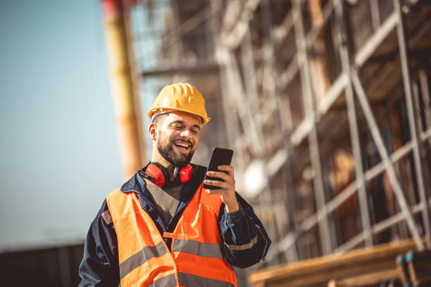istock Construction site manager standing  wearing safety vest and helmet,using his phone at construction site. 2151926712