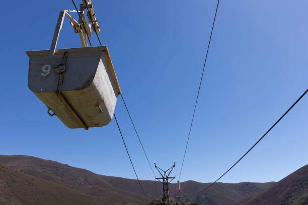 istock Abandoned industrial coal mining cart on cableway with rusty metal tower with cable on a bright sunny spring day with flower meadow 2151927110