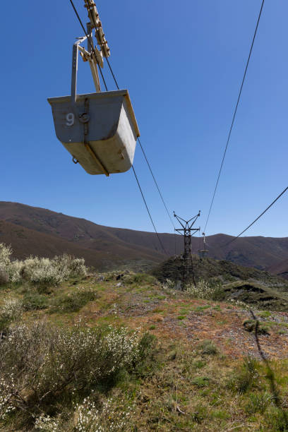 istock Abandoned industrial coal mining cart on cableway with rusty metal tower with cable on a bright sunny spring day with flower meadow 2151927113