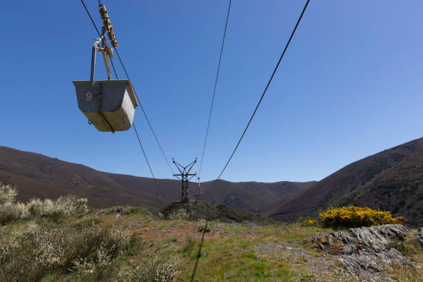 istock Abandoned industrial coal mining cart on cableway with rusty metal tower with cable on a bright sunny spring day with flower meadow 2151927119