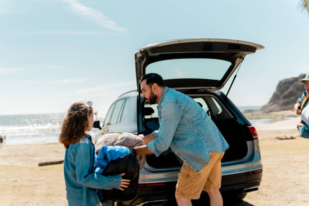 istock Father and kids unloading luggages from the car trunk on the beach 2151927176