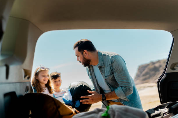 istock Family unloading luggages from the car trunk on the beach 2151927220