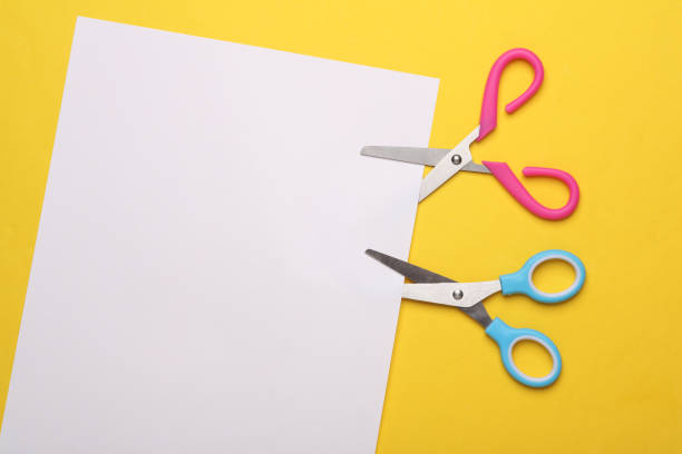 istock Scissors for creativity cut a white sheet of paper on a yellow background 2151927414