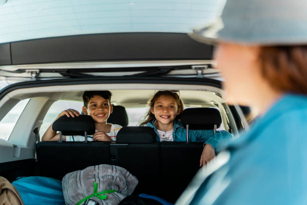 istock Child siblings talking to mother while she's unloading luggages from the car trunk during a trip 2151927898