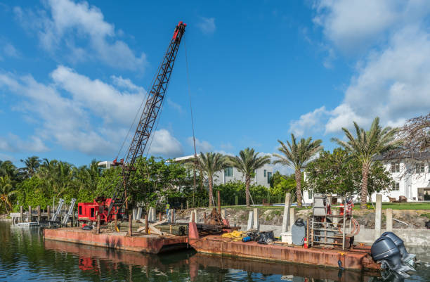 Crane barge doing work to raise retaining walls, to combat the rising tides caused by global warming, in an exclusive residential area of Miami Beach, Florida.