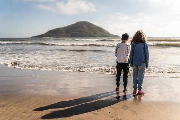 istock Child siblings relaxing and admiring the view on the beach 2151928605