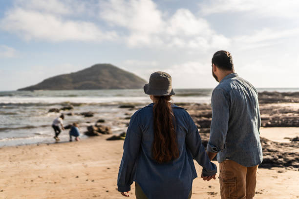 istock Parents holding hands and looking the kids playing on the beach 2151928609