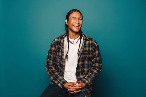 happy young man with braided hair and ethnic jewelry on blue background - índia imagens e fotografias de stock