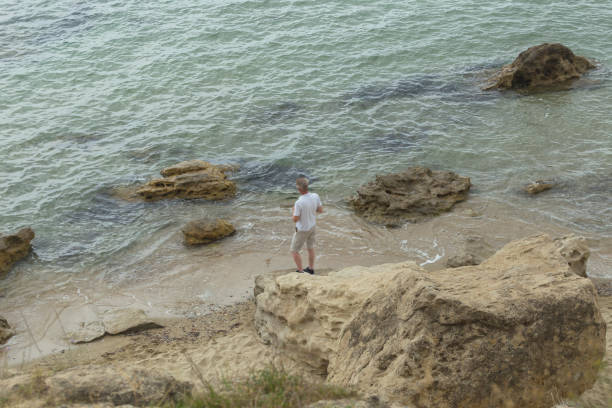 Man tourist relaxing and looking at view at Aegiean sea on overcast day