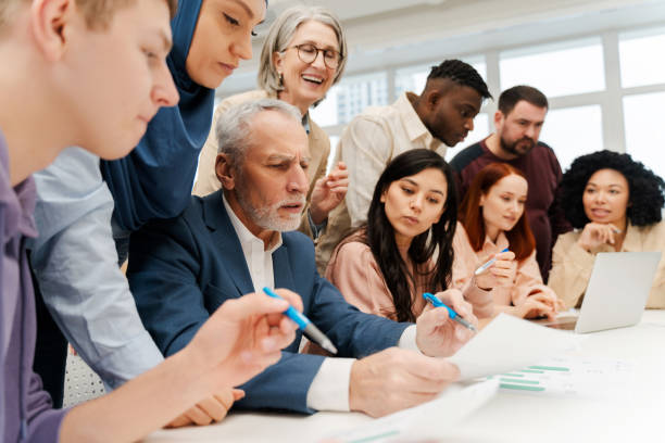 istock Group of multinational managers, CEO discussing together, holding report, sitting at desk 2151937237