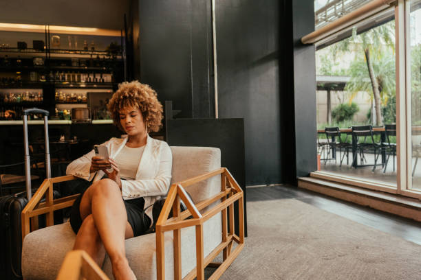 Businesswoman using smartphone sitting in hotel lobby