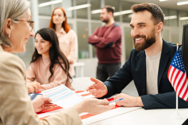 istock Smiling, bearded man sitting at registration table, talking with polling station worker, checking up 2151940164