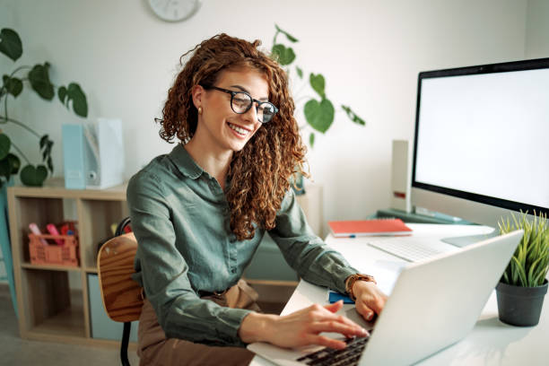 istock Cheerful well dressed businesswoman using laptop while working at the office 2151941486