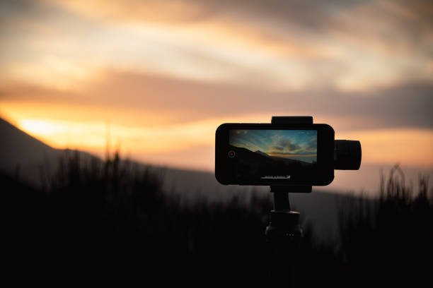 Smartphone on a tripod with active screen shooting sunset in the mountains. Using mobile phone to make sunset timelapse
