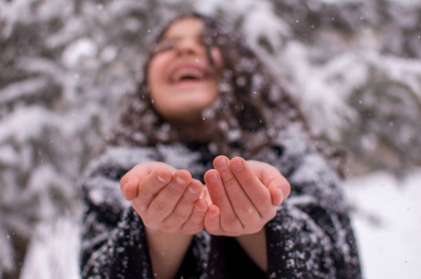 little cute girl with long hair in black dress having fun while snowing