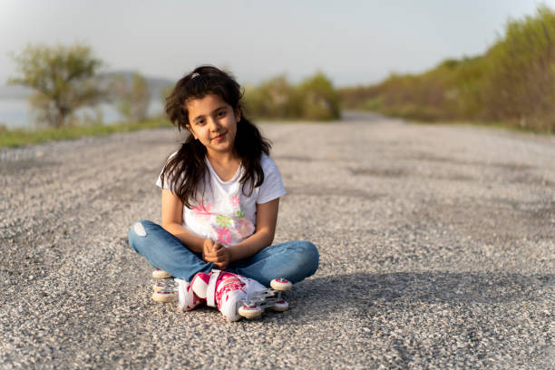 Girl in roller skates sitting in nature.