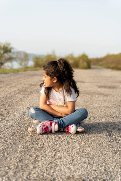 Girl in roller skates sitting in nature.