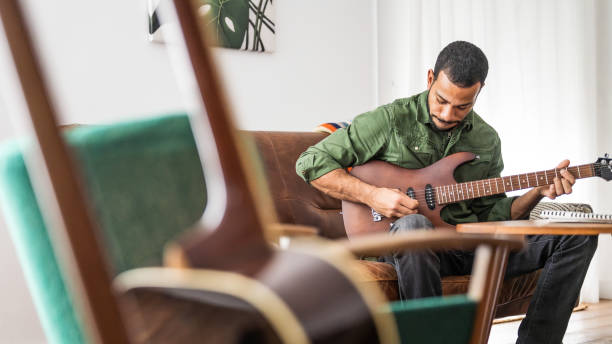 istock Black Man Engages with Electric Guitar in Home Environment 2151945728
