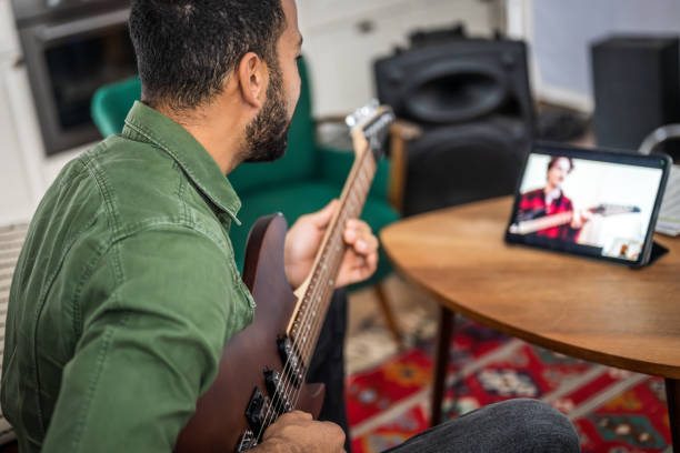 istock Musician Engages with Guitar Lesson at Home 2151945732