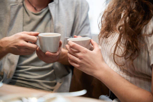 istock Couple is sitting in a restaurant holding coffee in their hands 2151948773