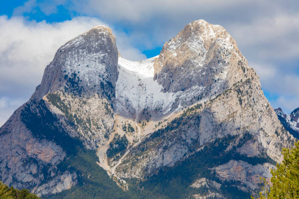 Pedraforca covered in snow, the winter is holding in 2024 springtime. The forest got the springtime colors, intense green everywere.Amazing mountain in Catalonia.
