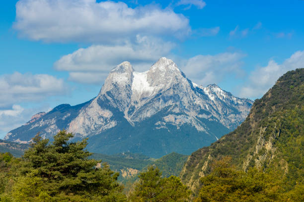 Pedraforca covered in snow, the winter is holding in 2024 springtime. The forest got the springtime colors, intense green everywere.Amazing mountain in Catalonia.