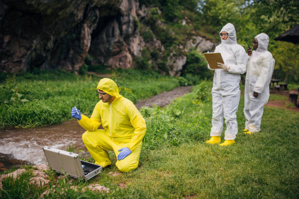 Environmental scientists in protective suits collecting water samples near a cave for conservation research to analyze ecosystem health