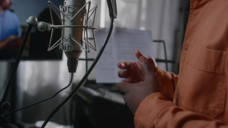 Hands of Black Male Voice Actor Dubbing Emotional Movie Scene in Studio