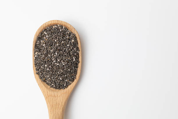 Organic chia seeds in a wooden spoon isolated against a white background.