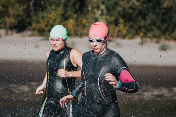istock Two female triathletes run into lake for open water swim 2151963377
