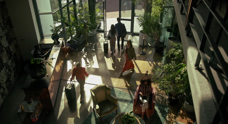 Business, people and walking or leave hotel for flight or journey, travel and end work trip with luggage or suitcase. Above man, women or accommodation for hospitality service, reception for booking.