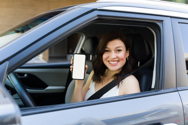 istock Cheerful female driver confidently presents blank smartphone screen while sitting in car, prepared for a drive 2151968584