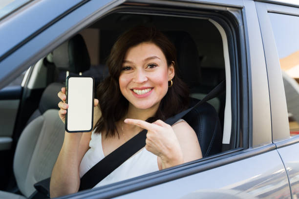 istock Happy woman confidently presents a smartphone with a blank screen while driving a car 2151968605
