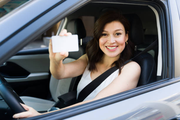istock Confident female driver happily displaying her driver's license in her car, radiating positivity on the road 2151968608