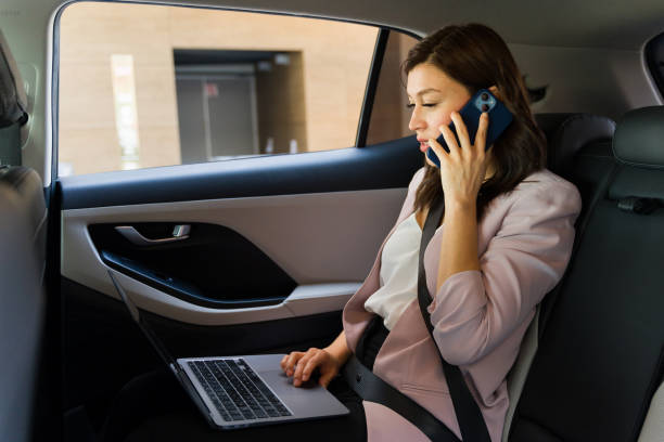 istock Efficient and productive businesswoman multitasking on laptop and smartphone during commute in car 2151969069